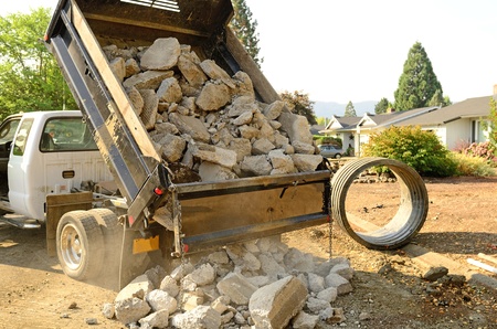 A small dump truck dumps concrete pieces during repair work following a broken water main leak from a fire hydrant base,の写真素材