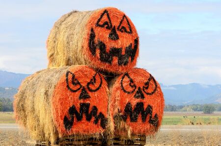 Large round hay bale jack o lantern halloween pumpkins at a roadside farm marketの写真素材
