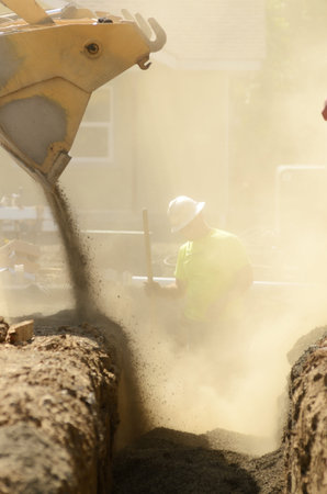 Infrastructure excavation building contractors installing water lines in a utility trench at a...