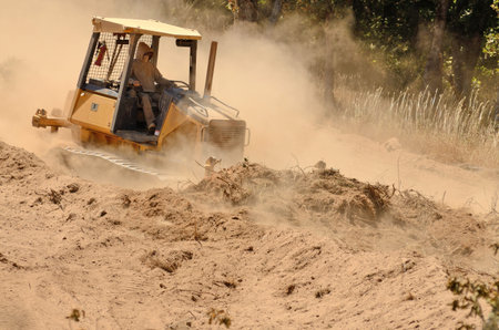 A small bulldozer works to remove top soil and duft with organic material from a new commercial...