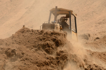 A small bulldozer works to remove top soil and duft with organic material from a new commercial...