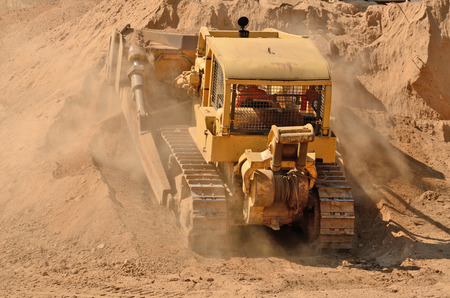 Large bulldozer excavating top soil for later use on a new commercial construction development projectの写真素材
