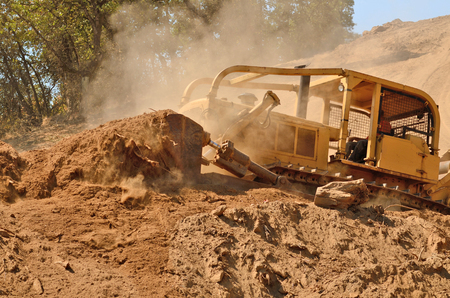 Large bulldozer excavating top soil for later use on a new commercial construction development projectの写真素材