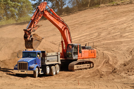 Track hoe excavator filling up a dump truck at  a new commerical construction development
