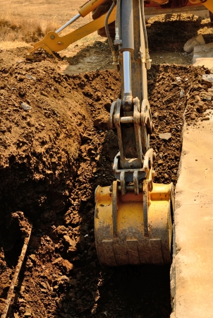 A backhoe and crew dig a utility trench for gas and other electrical utilities at a new commercial construction developmentの写真素材