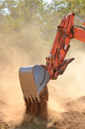 Large track hoe excavator moving rock and soil for fill for a new commercial development road construction projectの写真素材