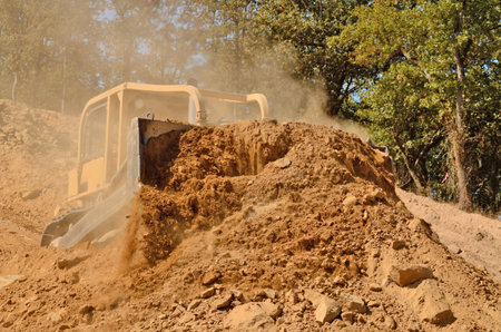 Large bulldozer moving rock and soil for fill for a new commercial development road construction...