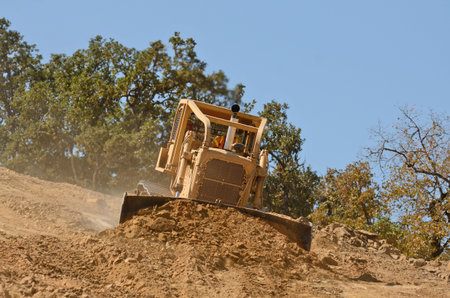 Large bulldozer moving rock and soil for fill for a new commercial development road construction...