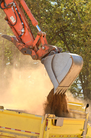 Large track hoe excavator filling a dump truck with rock and soil for fill for a new commercial...
