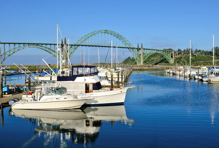 Waterfront marina full of commercial fishing boats at port with the Yaquina Bay Bridge in the background in Newport, Oregonのeditorial素材