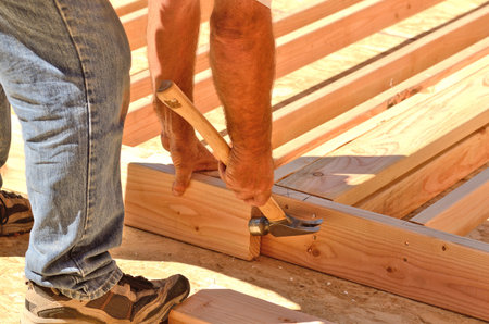 Building contractor worker using a air nail gun to attach studs to the top and base plate of the wall for the first floor on a new home construciton projectの写真素材