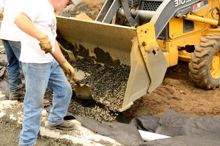  contractor installing a drainage system for a a wall using large concrete blocks to make a...