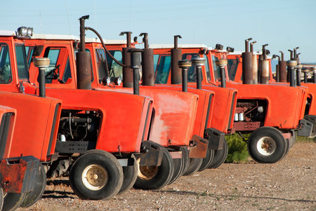 A line of red tractors waiting for work in a large agricultural equipment yard.の写真素材