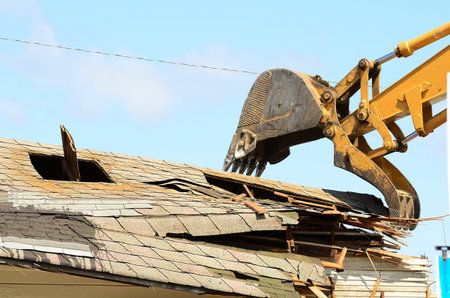 A large track hoe excavator tearing down an old hotel to make way for a new commercial development