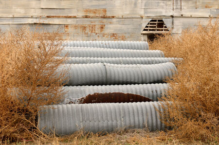 side of a old corugated metal industrail agricultural grain silo site and drain pipe culverts in northeast Texasの写真素材