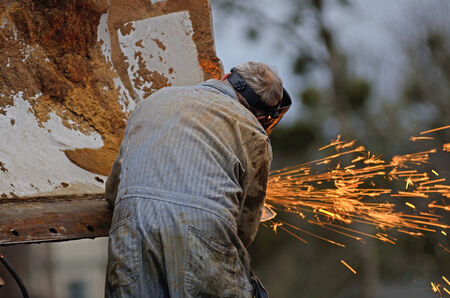 A mechanic welder uses a plasma cutter to cut metal plates from the blade of a bulldozer on a construction projectの写真素材