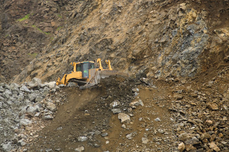 Large bulldozer moving large rocks to feed a rock crusher at a rock pit for gravel
