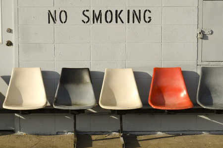 No smoking siting area outside a bus station with cigarette butts under chairsの写真素材