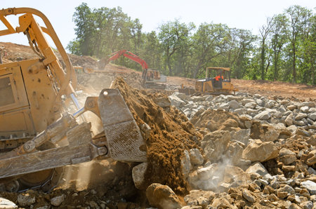 Large bulldozer moving rock and soil for fill for a new commercial development road construction...