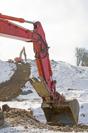Large excavator working the ground at a new commercial development following a snow storm