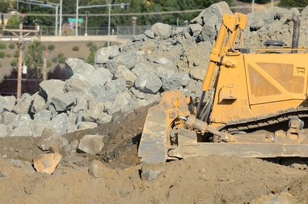 Tracked bulldozer working a rock pile at a large construction site removing a hill during an airport runway expansion projectの写真素材
