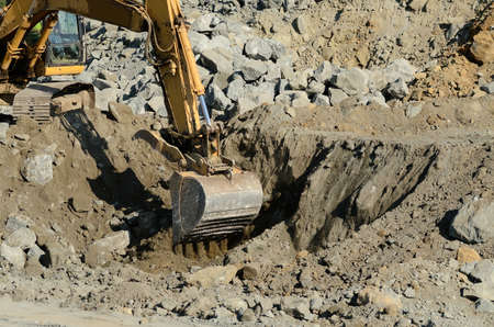 Tracked excavator or track hoe digging at a large construction site removing a hill during an airport runway expansion projectの写真素材