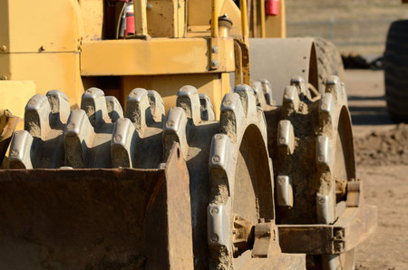 Detail of a dirt compactor at a large construction site removing a hill during an airport runway...
