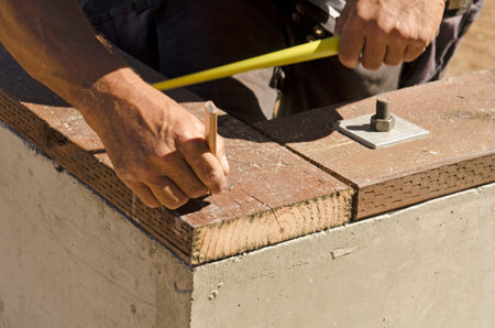 Framing contractor using a tape measure on a pressure treated sill plate on an new custom luxury...
