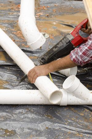 Plumbing building contractor installing plastic drain pipe in the floor section for a luxury custom houseの写真素材