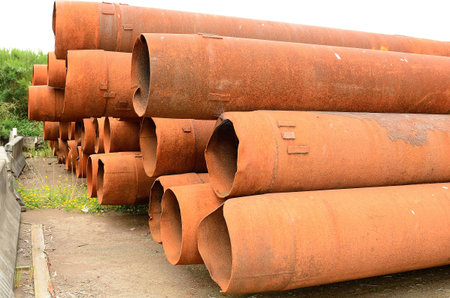 Large stack of rusty bridge pier pipes being stored in a dry dock area of Astoria Oregon