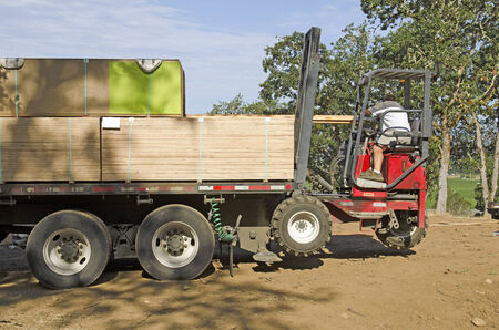 Truck mounted forklift or lift truck delivers building products to the site of new custom luxury homeの写真素材