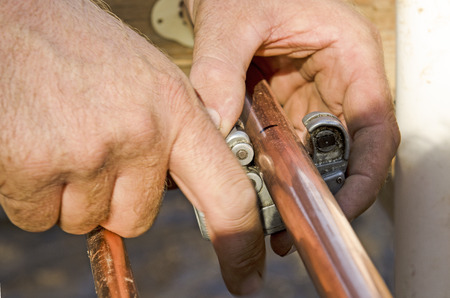 Plumbing contractor works cutting copper pipe domestic water system on a luxury custom homeの写真素材