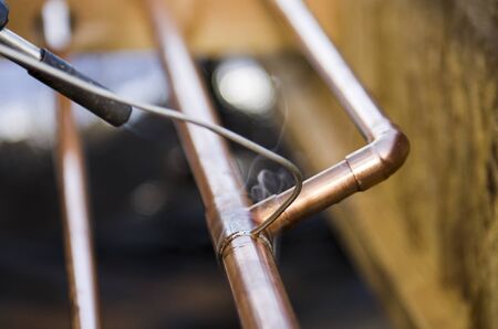 Plumbing contractor works sweating the joints on the copper pipe domestic water system on a luxury custom homeの写真素材