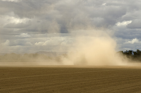 Large agricultural tractor pulling a steel disc harrow to prep the soil for planting with fall storm approachingの写真素材