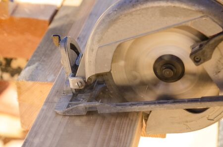 Building contractor worker using hand held worm drive circular saw to cut boards on a new home construction projectの写真素材