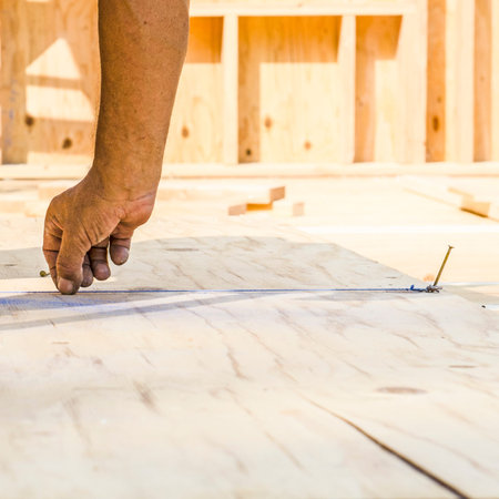 Framing contractor measuring and  chalk line to install plywood sub siding to wood joistの写真素材