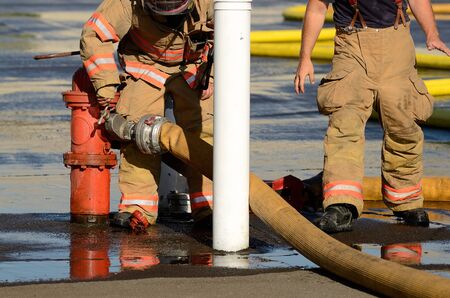 Firefighters at the fire hydrant while using large volume appliance water delivery master streamsの写真素材