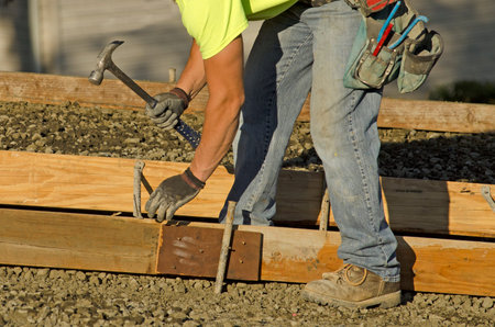 Concrete construction contractor installing a sidewalk, curb and storm drainage gutter forms on a...