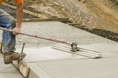 Concrete construction contractor using a float to  smooth a sidewalkの写真素材