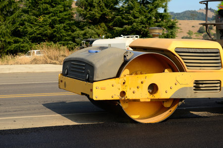 Drum tandem vibratory rollers compacting down a fresh layer of paving on a new road interchange...