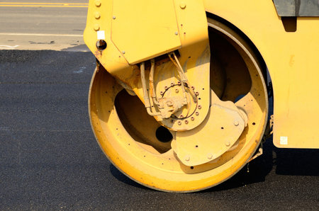 Drum tandem vibratory rollers compacting down a fresh layer of paving on a new road interchange...