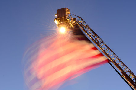 Large american flag at the top of a fire department ladder fire truck at a independence day...