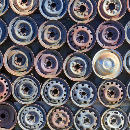 Wall of metal vehicle drive wheels on a tire recycle shopの写真素材
