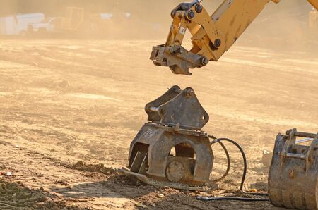 Backhoe hooking up to a powered compactor at a new commercial housing develpmentの写真素材