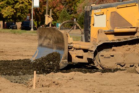 Small bulldozer moving rock and soil in a new commercial housing developmentの写真素材