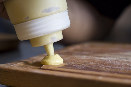 Preparation of a dish, putting mustard in a wooden boardの写真素材