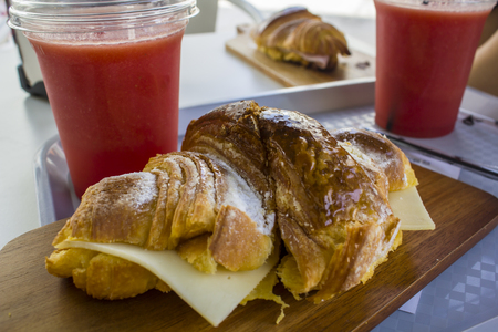 Freshly baked Croissant with cheese and natural watermelon juice on a plastic cupの写真素材