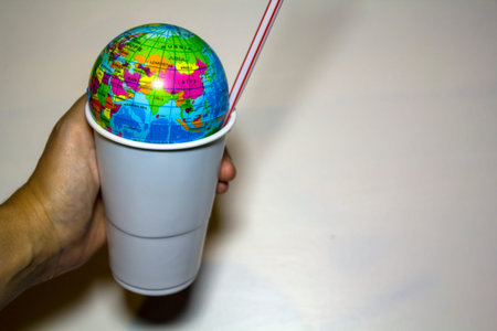 World on a plastic cup and a plastic straw. Plastic pollution concept