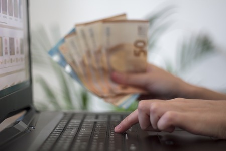 Hands holding euro money and using laptop. Concept of business and Online shoppingの写真素材