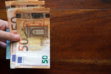 Handsholding euro banknotes. Top view above office desk